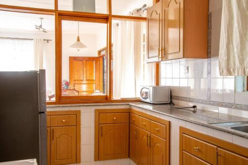 a kitchen with wooden cabinets and a black refrigerator at Unique 2BR United Nation bluezone perimeter in Nairobi