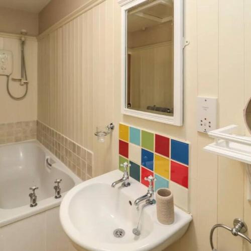 een badkamer met een wastafel, een bad en een spiegel bij Beautiful Countryside Cottage Alnwick in Alnwick