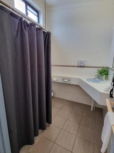 a bathroom with a black shower curtain and a sink at Y Motels Yarraman in Yarraman