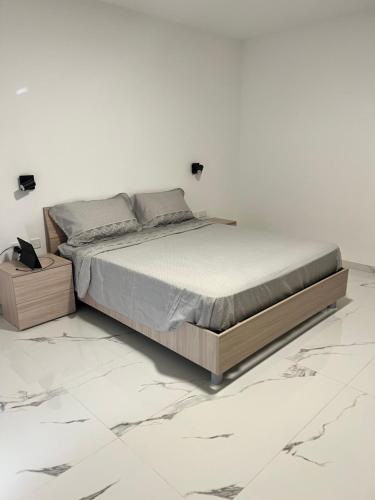 a bed in a white bedroom with marble floors at Penthouse with 3 bedroom in Luqa