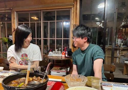 two people are standing around a pot of food at Homey Inn Enya in Yufuin