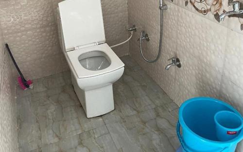 uma casa de banho com um WC e uma lata de lixo azul em Hotel Village Inn by StayApart em Barkot