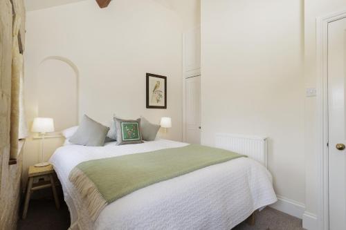 a bedroom with a white bed with a green blanket at The Carriage House in Blockley