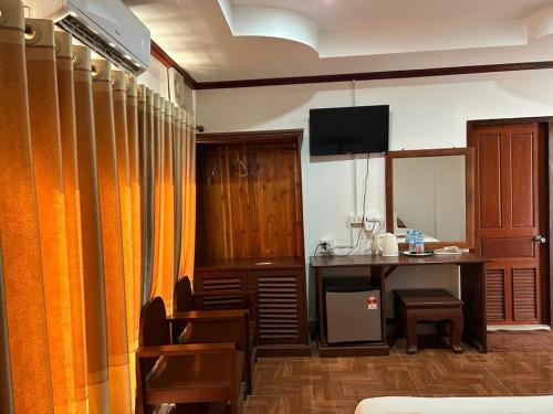 Cette chambre comprend un bureau et une table avec des chaises. dans l'établissement SISAVANG HOTEL, à Vang Vieng