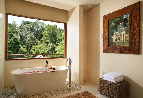 y baño con bañera y ventana grande. en Cicada Luxury Resort - Ubud en Tegalalang