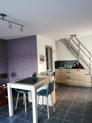 eine Küche mit einem Tisch und Stühlen sowie eine Treppe in der Unterkunft Appartement 2-3 personnes sur la côte d'Emeraude in Saint-Cast-le-Guildo