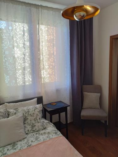 a bedroom with a bed and a chair and a window at Roses Apartment in Frýdek-Místek
