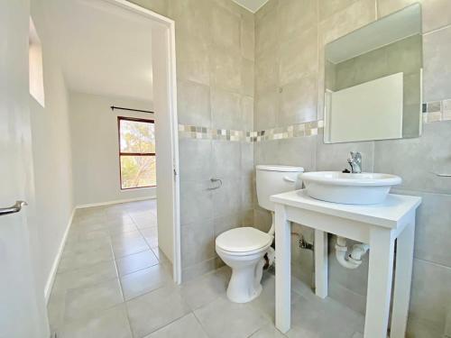 a bathroom with a white toilet and a sink at Laguna Beach K60 - Greenways Golf Estate on Sea in Cape Town