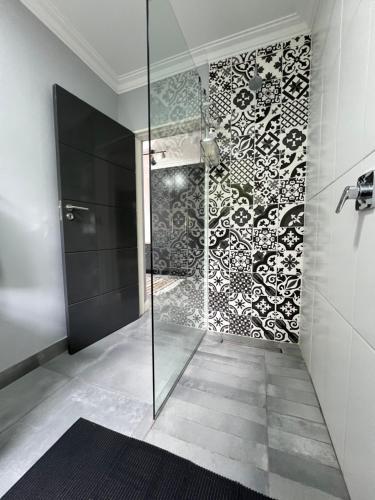 La salle de bains est pourvue d'une douche avec une porte en verre. dans l'établissement Afrique134 Baobab Tree Private Family Garden Suite, à Pretoria