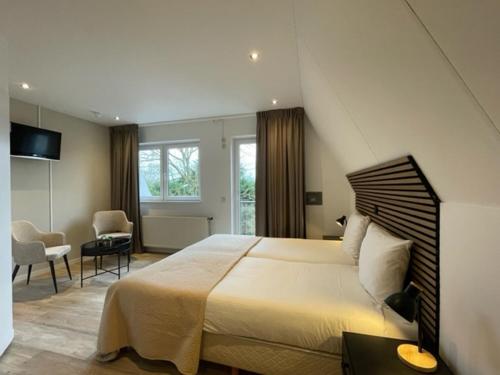 a bedroom with a large bed and a living room at Hotel Randduin in Oostkapelle
