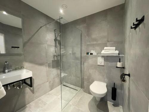 een badkamer met een douche, een toilet en een wastafel bij Hotel Randduin in Oostkapelle