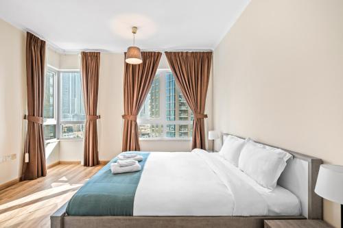 a bedroom with a bed and two windows at Fountainview Luxe 1BR, sleeps 4 in Dubai