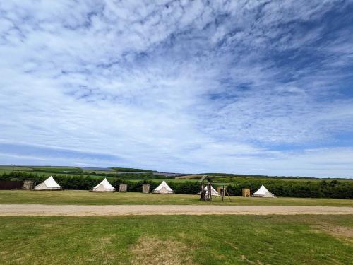 eine Gruppe von Zelten auf einem Feld unter einem wolkigen Himmel in der Unterkunft Penhallow Glampsite in Truro