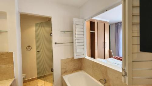 a bathroom with a bath tub and a mirror at Sandhurst Towers in Johannesburg