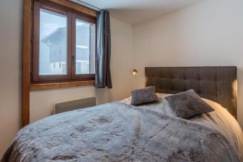 um quarto com uma cama grande e uma janela em Megève - Appartement - 1 Chambre em Demi-Quartier