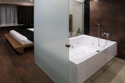a bathroom with a bath tub and a bedroom at Grand Kailash Hotel in Aurangabad