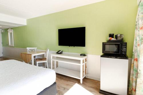 ein Schlafzimmer mit einem Bett und einem TV an der Wand in der Unterkunft Superb 3rd Floor Oceanfront King Room in Pawleys Island