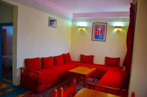 a living room with a red couch and a table at Hôtel Auberge du Littoral in Aourir