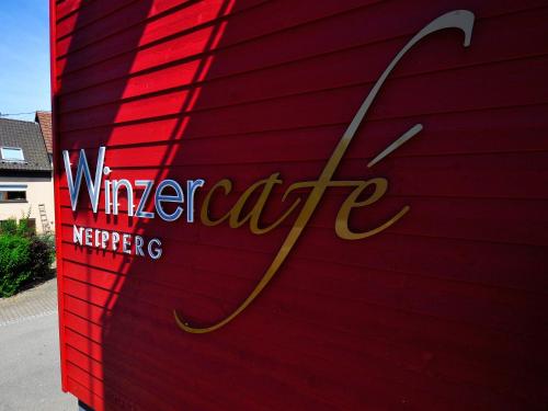 Brackenheim的住宿－Winzercafe Neipperg Ferienwohnungen，红色的墙,有葡萄园的慈悲标志