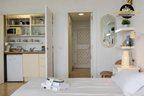 a bedroom with a white bed and a kitchen at Apartamento Castillo Santa Clara 1º Linea El Trasval in Torremolinos