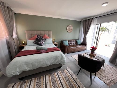a bedroom with a bed and a chair and a couch at Afrique134 Olive Tree Private Courtyard Suite in Pretoria