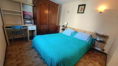 um quarto com uma cama azul e uma secretária em Maison de pêcheur en plein centre ville. em Valras-Plage