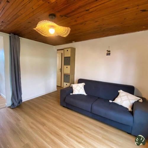 a blue couch in a living room with a wooden ceiling at La Tit'Kaz Bégonia (Vue montagne) in Saint-Philippe