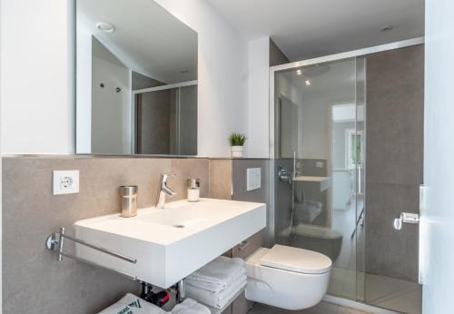 een badkamer met een wastafel, een toilet en een spiegel bij Apartamento Ponent 1 in Cala Ratjada