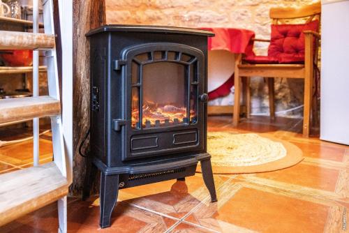 a black stove in a room with a fireplace at Le Pigeonnier - Piscine - Jardin - Calme in Labastide-de-Lévis