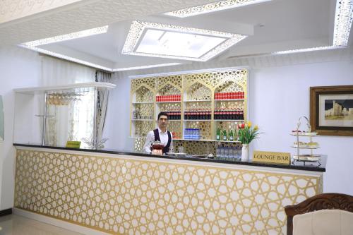 a man standing behind a bar in a room at Poykent Naqshband in Bukhara