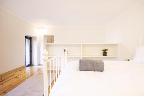 a white bedroom with a white bed and a staircase at Alma Peregrina - Casas de Campo in Junqueira