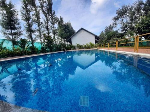 una piscina de agua azul frente a una casa en Four Seasons Resort, en Kushālnagar