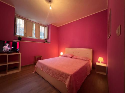 Habitación de color rosa con cama y TV en Tavernetta Cortile Dalmazia, en Catania