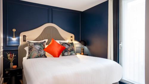 a bedroom with blue walls and a white bed with pillows at Residhome Paris Opéra in Paris