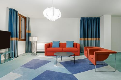 Palazzo Dei Fiori by Room Mate في البندقية: غرفة معيشة مع أريكة حمراء وطاولة