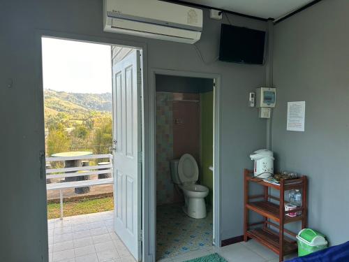 a bathroom with a toilet and a balcony with a television at โดมเขาค้อ in Ban Thung Samo