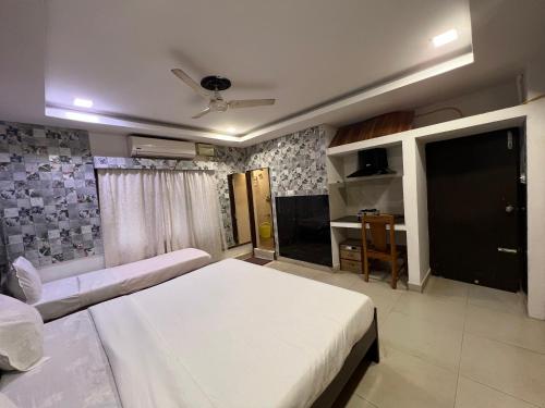 a bedroom with a white bed and a tv at Vishranthi Home Stay in Chennai