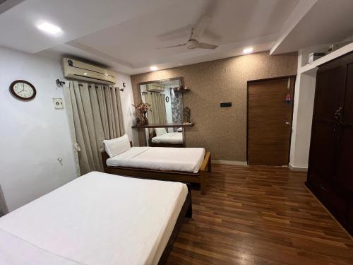 una camera con due letti e un orologio a muro di Vishranthi Home Stay a Chennai