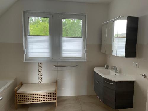 ein Badezimmer mit einem Waschbecken und zwei Fenstern in der Unterkunft Urlaub am Plätlinsee - Haus Odin in Wustrow
