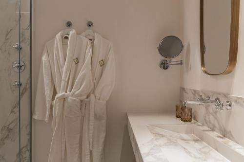 a bathroom with a robe hanging next to a sink at De Lindenhoeve Boutique Hotel in Sluis