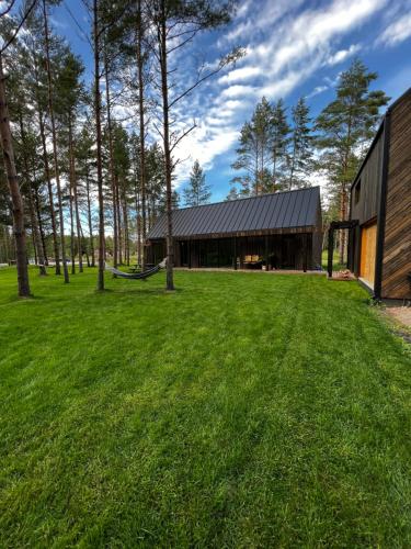 a house with a green lawn in front of a building at Peaceful holiday house Pāvilosta in Pāvilosta