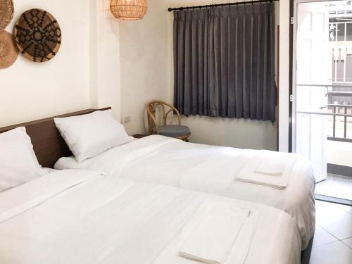 清邁的住宿－บ้านสวนอินทาวน์ Baansuan in Town Hotel，一间卧室设有两张白色的床和窗户