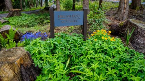 a sign in the middle of a garden with flowers at Heilan Roo in Pitlochry