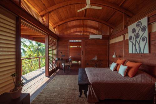 a bedroom with a bed in a room with a balcony at Cabo Serai in Canacona