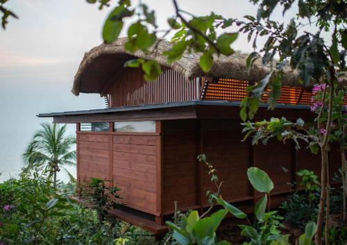 a small house with a thatched roof on a hill at Cabo Serai in Canacona