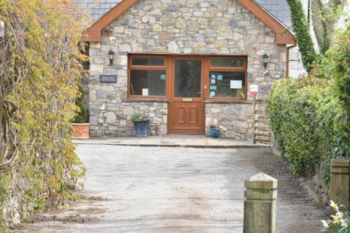 a stone house with a brown wooden door at Ballas Farm Country Guest House in Bridgend