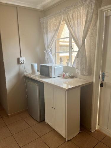 a kitchen with a counter with a microwave and a window at Always Here for you in Krugersdorp