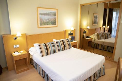 Habitación de hotel con cama y espejo en Hotel Alda Castelao en Vilagarcia de Arousa