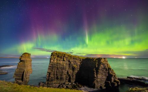 an image of the aurora over the ocean with a rock formation at Harbourside by Caithness Luxury Apartments NC500 - 2 Bedroom holiday home - Sleeps Work teams upto 2 & holiday makers upto 6 with bike store in Wick