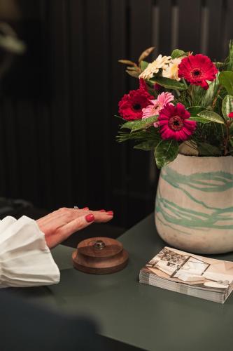 a hand pointing at a vase with flowers on a table at De Lindenhoeve Boutique Hotel in Sluis